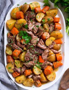 a white plate topped with meat and veggies on top of a marble counter