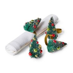 three napkin rings decorated with christmas trees and balls on top of each other next to a white napkin