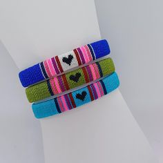 three bracelets with hearts are stacked on top of each other in different colors and designs