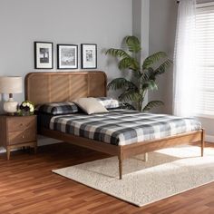 a bed sitting on top of a hard wood floor next to a wooden dresser and lamp