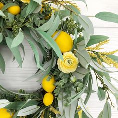 a wreath with lemons, eucalyptus leaves and yellow flowers on a white wooden background