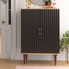 a brown cabinet sitting on top of a hard wood floor next to a white door