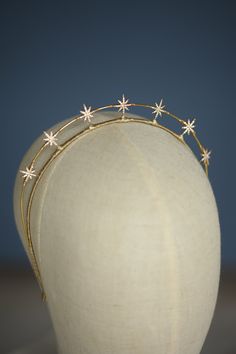 a white mannequin head with three gold stars on it's forehead and two other hair accessories