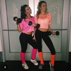 two women in pink shirts and black leggings holding dumbbells while standing next to each other