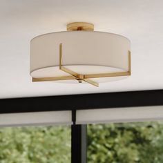 a ceiling light with a white shade hanging from it's center point in front of a window