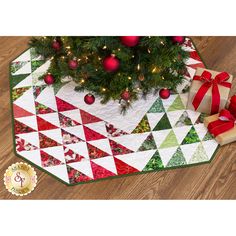 a christmas tree with presents under it on the floor next to a red and white ribbon