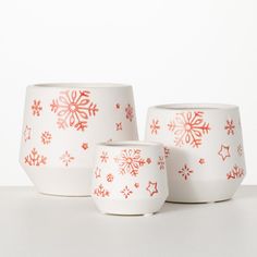 three white bowls with red snowflakes on them