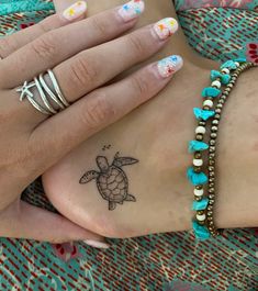 a woman's foot with a turtle tattoo on her left hand and two bracelets around her ankles