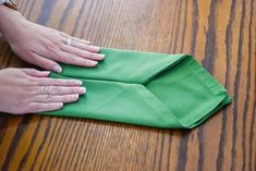 two hands are holding green napkins on a wooden table