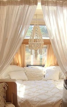 a white bed sitting under a window next to a chandelier