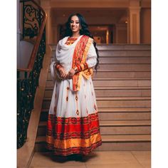 This exquisite Ethiopian Habesha dress is a true masterpiece of traditional craftsmanship. The lower part of the dress is made of Shimena, which is handwoven with great care and attention to detail, resulting in a beautiful and unique texture. The Menen fabric used in this dress is of the highest quality, adding a luxurious feel to the overall design. The neckline and wrists of the dress are adorned with intricate Tilf embroidery, adding an elegant and sophisticated touch to the vibrant colors o Traditional Long Handloom Dress, Traditional Long Dresses For Transitional Season, Traditional Maxi Dress With Drape For Festivals, Traditional Floor-length Maxi Dress For Transitional Season, Traditional Maxi Dress For Navratri Ceremonies, Traditional Maxi Dress With Traditional Patterns For Festive Occasions, Festive Traditional Pattern Maxi Dress For Ceremonies, Traditional Maxi Dress For Festive Ceremonies, Festive Maxi Dress With Traditional Patterns For Ceremonies