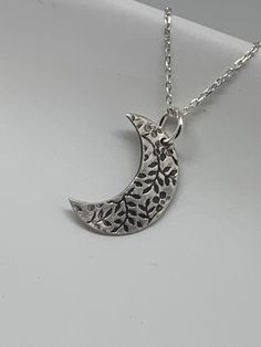 This unique silver moon necklace has been entirely handmade using .999 fine silver. It has been cut from fine silver precious metal clay, textured, fired and oxidized. The pendant hangs from a sterling silver diamond cut cable chain. This fine silver pendant features an embossed leaf print pattern and hangs 7/8 inches from top of ring to bottom of the moon shape. Pendant size: approximately 5/8 x 1/2 inches Chain length: adjustable at 16 and 18 inches can also be customized to whatever length ne Silver Etched Nature-inspired Necklaces, Sterling Silver Moon Engraved Necklace, Nature-inspired Silver Etched Necklaces, Sterling Silver Moon Shaped Engraved Necklace, Unique Moon-shaped Engraved Necklace, Unique Moon Shaped Engraved Necklace, Unique Engraved Moon-shaped Necklace, Artisan Moon Charm Necklaces, Artisan Silver Necklace With Moon Phase