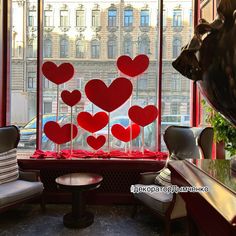 the window is decorated with red hearts and sticks in front of it, along with two chairs