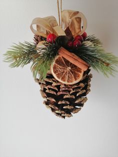 a pine cone ornament hanging on a wall with cinnamons and orange slices