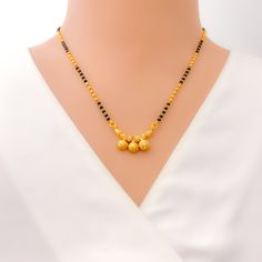 This 22k gold mangal sutra, weighing 9.1 grams, boasts a striking combination of traditional design and modern elegance. Its black bead accents complement the yellow gold finish, while the 16-inch necklace length ensures a graceful fit. The 0.25-inch drop adds a subtle yet captivating detail, and the secure hook lock offers both comfort and convenience. Perfect for symbolizing marital unity with a contemporary twist, this piece is ideal for any special occasion, blending cultural significance with timeless beauty. PRODUCT DETAILS Gold Purity(karat): 22k Item Weight(grams): 9.1 Item Finish: Yellow Gold Stone: Black Bead Necklace Length: 16" Drop Length: 0.25" Lock Style: Hook Lock Elegant Black Temple Necklace As Gift, Elegant Black Temple Necklace For Wedding, Elegant Black Temple Necklace Gift, Black 22k Gold Jewelry As A Gift, Black 22k Gold Jewelry For Wedding, Yellow Gold Necklace With Black Beads As Gift, Black 22k Gold Wedding Jewelry, Elegant Yellow Necklace For Puja, Festive Gold Necklaces With Black Beads