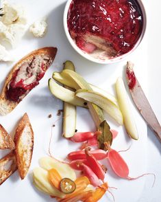 a white plate topped with fruit and vegetables next to a bowl of sauce on top of it