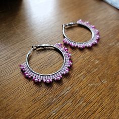 Hand woven hoop earrings created with White crystal pearls and fine glass seed beads in shades of Pink delicately woven onto Stainless Steel hoops.     👉  Arrives in a gift box with bow, ready for giving. 🎁 👉  Measurements:  2 inches around. 👉  Lightweight and easy to wear 👉  304 Stainless Steel hoops 👉  Miyuki and Toho glass seed beads 👉  White crystal pearls 👉  Thermally-fused extra strong thread For different colorways and styles, visit my shop:  https://www.etsy.com/shop/CyntheCreations ⭐  THINGS TO KNOW ABOUT BEADED JEWELRY:  While sealed for normal wear, glass beads are NOT WATERPROOF and should not be worn when swimming or bathing.      Pattern Design by Breanna Deis Silver Beaded Hoop Earrings As Gift, Pink Metal Dangle Beaded Earrings, Pink Hoop Beaded Earrings For Party, Pink Beaded Metal Earrings, Festive Beaded Hoop Earrings With Round Beads, Festive Beaded Hoop Earrings, Metal Beaded Earrings With Round Beads For Festivals, Metal Beaded Earrings For Festivals, Festival Metal Beaded Earrings With Round Beads