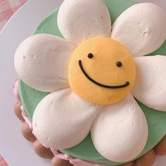 a cake decorated with white and green icing has a smiley face on it's center