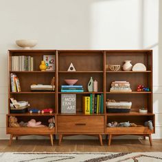 a bookshelf filled with lots of books on top of a hard wood floor