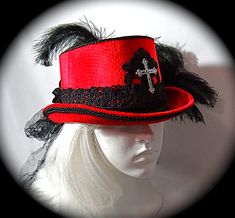 "This Gothic top hat is heavy red velvet wrapped with a black velvet and lace hatband and has a soft black crushed tulle bow & long tails in back. This Victorian style riding hat has black satin roses centered in the back.  There is a silver antiqued Celtic cross centered on a beautiful black lace applique on the front of the crown. A black lace applique rests on the back of the crown's top. The brim & crown edge are trimmed in black satin braid. This hat is loaded with black curled ostrich plumes and measures 23\".  All of the pieces you see in my shop are my original designs and carefully crafted for your pleasure... be sure to contact me for any special requests you may have! For a look at my complete Women's Hat Collection click on this link.... https://www.etsy.com/your/shops/Marcelle Fitted Top Hat With Short Brim For Costume Party, Fitted Wide Brim Top Hat For Halloween, Fitted Hat Bands For Costume Party, Red Fitted Hat For Costume, Red Fitted Top Hat For Winter, Wide Brim Fitted Top Hat For Halloween, Red Fitted Mini Hat For Costume Party, Gothic Top Hat With Short Brim For Halloween, Gothic Top Hat With Short Brim For Costume Party