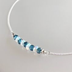 Genuine welo opal and london blue topaz bar choker/necklace in sterling silver This necklace features genuine ethiopian opals and london blue topaz gemstones arranged in a bar that is wire-wrapped to a delicate but sturdy sterling silver chain; secured with a lobster claw clasp.  The beaded bar is designed with a slight curve for a smooth drape and perfect fit.  The london blue topaz are permanently coated white topaz beads. An elegantly subtle necklace that can easily be worn by itself or paired with others for a layered look.  Details: necklace length: please choose desired length at check-out london blue topaz: approx. 4 mm welo opal: approx. 3.5 - 4 mm sterling silver chain and other components Thanks for visiting ! Back to my shop for more jewelry options: www.etsy.com/shop/krisatdesi Cheap White Christmas Necklace, Cheap Blue Beaded Necklace For Gifting, Cheap Blue Beaded Necklace For Gift, Cheap Elegant Sterling Silver Beaded Necklaces, Cheap Blue Chain Jewelry, Opal Bar Necklace, London Blue Topaz Necklace, Blue Topaz Necklace, Garnet Bracelet