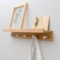 a white bag hanging on a wall next to a wooden shelf with a picture frame