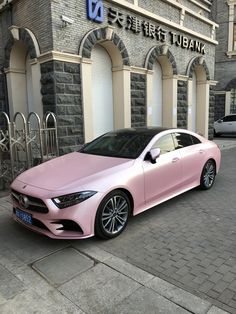 a pink car parked in front of a building