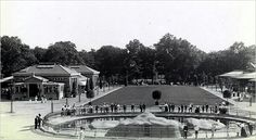 an old black and white photo of people standing in front of a fountain