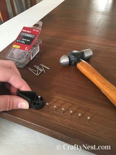 a person is working with some screws on a wooden table next to a hammer and pliers