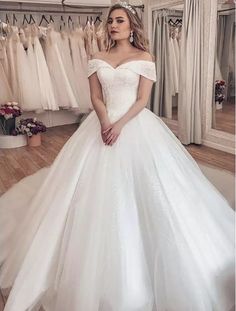 a woman in a white wedding dress standing next to a rack with dresses on it