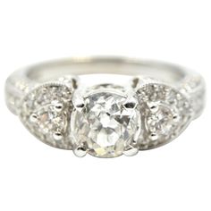 This ring is made in 14k white gold, and it holds a 0.91-carat European cut diamond. The stone is graded J in color and SI1 in clarity. The mounting is then set with 44 smaller round diamonds for an additional weight of 0.85ct. The ring also features open filigree in the mounting. The ring measures 6.5mm at its widest point, weighs 5.08 grams and is a size 6. Gia Certified Heart Cut Diamond Anniversary Ring, White Diamond Ring With Vvs Clarity, Heart Cut, Gia Certified 14k White Gold Cluster Ring, White Heart Cut Diamond Ring With Vvs Clarity, Gia Certified Diamond White Diamond Ring, Gia Certified Diamond Cluster Ring, Platinum Diamond Ring With Heart-shaped Brilliant Cut, Gia Certified Silver Ring With Lab Grown Diamond, Silver Halo Ring With Brilliant Cut In Platinum