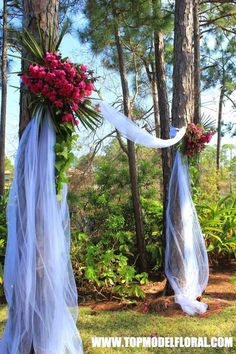 the wedding arch is decorated with flowers and tulle for an outdoor ceremony in the woods