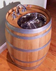 three wooden barrels with water in them sitting on the floor next to a door and one has a sink