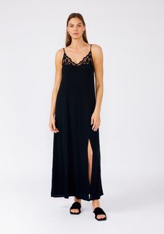 [Color: Black] A front facing image of a brunette model wearing a classic black maxi slip dress with lace detail along the neckline. With adjustable spaghetti straps Chic V-neck Maxi Dress With Lace Trim, Spring Delicate Lace V-neck Slip Dress, Black Slip Dress With Side Slits, Elegant V-neck Maxi Dress With Lace Trim, Midi Length Slip Dress With Lace Trim For Daywear, V-neck Slip Dress With Lace Trim For Date Night, Lace V-neck Slip Dress With Bias Cut, V-neck Lace Trim Slip Dress For Date Night, Elegant Maxi Length Dresses For Night