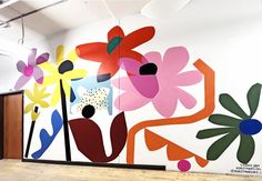 a large colorful painting on the side of a wall next to a wooden floor in an office building