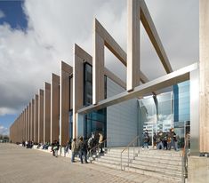 many people are walking up and down the stairs to an open air building with large windows