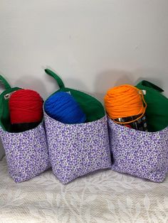 three baskets with balls of yarn and crochet hooks on top of a bed