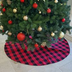 a christmas tree with red and gold ornaments on it's top, sitting in front of a window