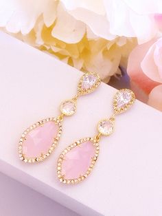 two pairs of earrings with pink stones and gold trimmings on a white surface