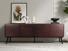 a sideboard with vases sitting on top of it next to a potted plant