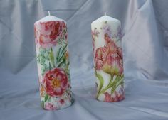 two candles with flowers painted on them sitting next to each other