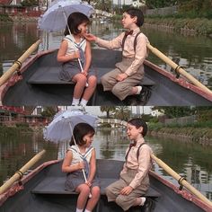 two children sitting in a boat with an umbrella and another child on the other side