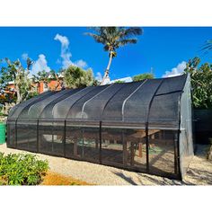 a large green house sitting on top of a lush green field next to palm trees