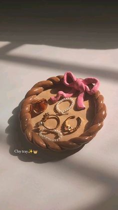 a wooden tray with rings and other jewelry on top of it, sitting on a white surface