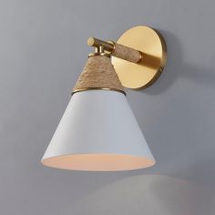 a white and gold wall light on a gray wall with a wooden stick sticking out of it