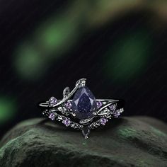 a purple diamond ring sitting on top of a rock