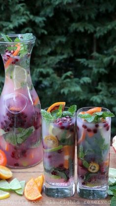 three glasses filled with liquid and fruit on a table next to some oranges, limes, and other fruits