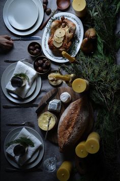 a table topped with plates and bowls filled with food next to other dishes covered in greenery