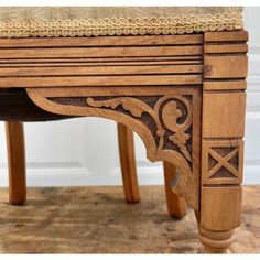 an old wooden table with carvings on the top and bottom, sitting on a hard wood floor