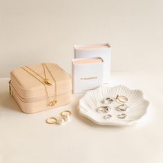 the jewelry box is next to two pairs of gold rings and a pair of earrings